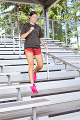 Young Woman running up and down bleacher stairs at a stadium training for her high school sports season. Young woman working to stay fit and healthy.