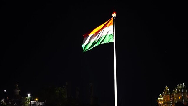 Indian tri color with saffron green white and ashoka chakra waving in the wind against the black night sky showing the independence and republic day of the world's largest demography
