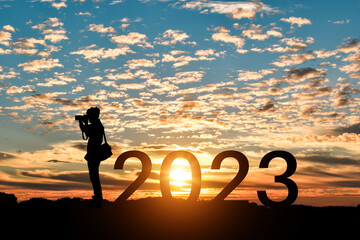 Silhouette of photographer taking photos in 2023 years at sunrise or sunset background. Idea for...