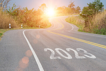 New year 2023 forward concept. Word 2023 written on the asphalt road at sunset sky. Concept of planning, challenge and goal.
