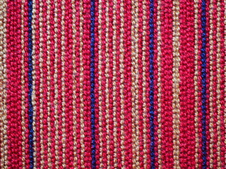 A piece of fabric placemat with colourful (red, navy, beige) pattern line.