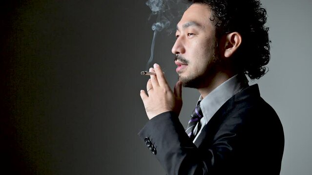 煙草を吸うダンディな男性の横顔の動画　コピースペースあり