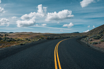 road in the desert with clouds in the blue sky
