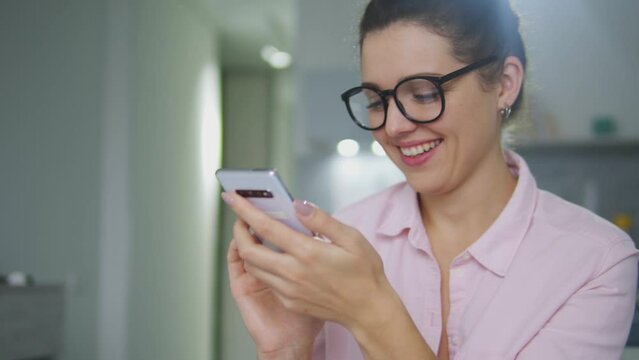 Attractive young woman laughing coquettishly texting with boyfriend on phone