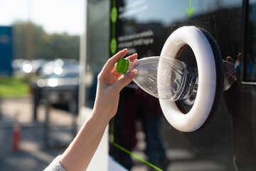 Woman uses a self service machine to receive used plastic bottles and cans on a city street	