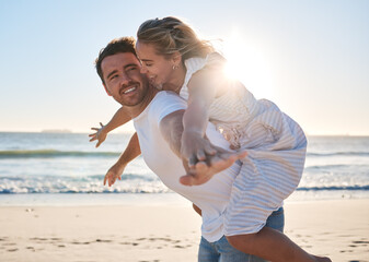 Happy, couple and piggyback walk on the beach for love, travel or summer vacation bonding together in the outdoors. Man carrying woman on back with smile enjoying playful fun time walking by the sea