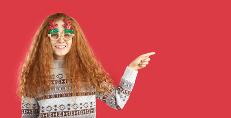 Girl inviting check-out holiday prices and special Christmas discounts by pointing to place for...