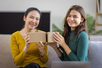 Two Asian women to Startup small business SME entrepreneur of freelance working on laptop computer with parcel box on table laptop at home, online marketing packaging and delivery SME idea concept