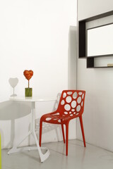 Corner with red chair and white table with 