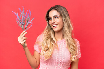 Young pretty Uruguayan woman holding lavender isolated on red background with happy expression