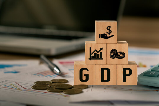 GDP, Gross Domestic Product symbol, word 'GDP' in a wooden block and computer-backed background.  There was a coin placed beside the wooden block.  The concept of gross domestic product, or GDP.