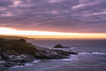 Dramatic landscape sunrise image at Prussia Cove in Cornwall England with atmospheric sky and ocean
