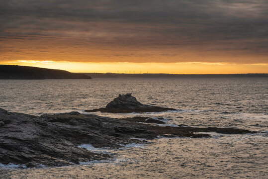 Dramatic landscape sunrise image at Prussia Cove in Cornwall England with atmospheric sky and ocean