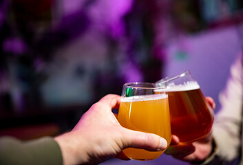 Two friends hands with glasses of craft beer at the pub or bar. taproom