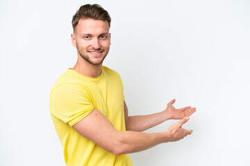 Young blonde caucasian man isolated on white background extending hands to the side for inviting to come