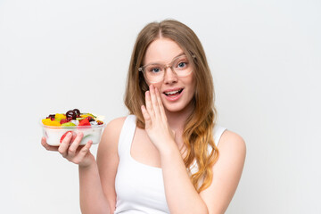 Young pretty woman holding a bowl of fruit isolated on white background whispering something