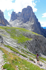 Fototapeta na wymiar woman with backpack walks on the gravel path in the italian alps