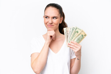 Young caucasian woman taking a lot of money isolated on white background having doubts and thinking
