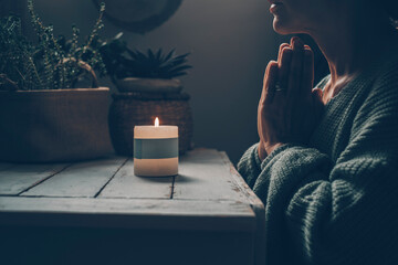 Zen like lifestyle meditation in front of a candle light praying for one woman at home. Green mood...