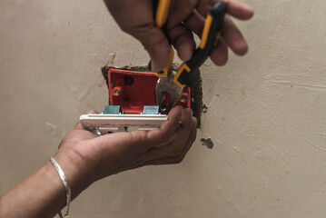 An electrician installs a new replacement electrical outlet, hooking up the wires. 240 volt receptacle in the living room.