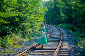 one girl in a green dress is walking on the railway