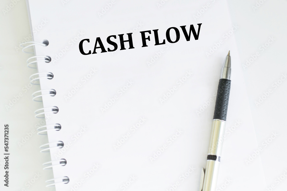 Aufkleber cash flow text on a notebook on a table next to a pen, a business concept