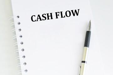 Cash Flow text on a notebook on a table next to a pen, a business concept
