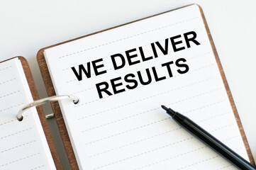 WE DELIVER RESULTS text written on sticky with pencil and glasses