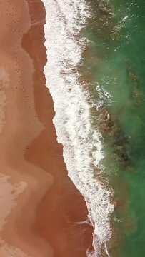 Aerial view on ocean waves and sand beach on the Atlantic coast in Morocco. Vertical video