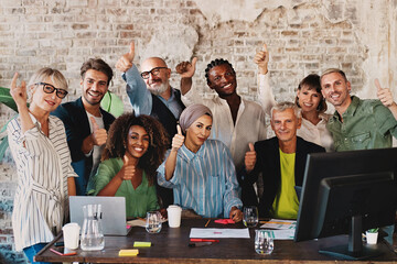 Multiethnic group of business colleagues posing thumb up sitting at the office desk