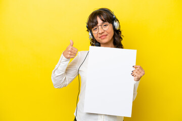 Telemarketer latin woman working with a headset isolated on yellow background holding an empty placard with thumb up