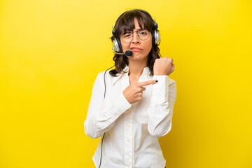 Telemarketer latin woman working with a headset isolated on yellow background