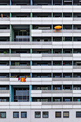 Frontalaufnahme eines Wohnkomplexes mit bunten Tüchern und Schirmen auf den Balkonen