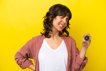 Young latin woman holding compass isolated on yellow background suffering from backache for having made an effort