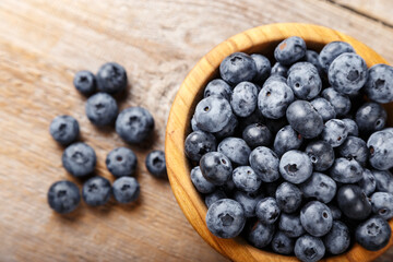 Freshly picked blueberries in a wooden bowl. Healthy food and nutrition concept.