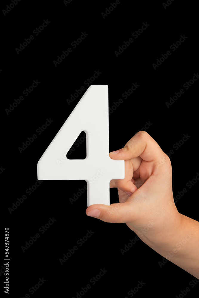 Poster number four in hand isolated on black background. number four in a child's hand, holding on a black 