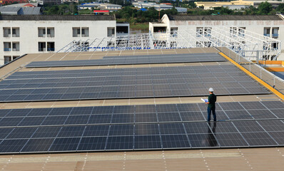 Electrical engineer standing on the factory roof holding paper roll examining correct installation...