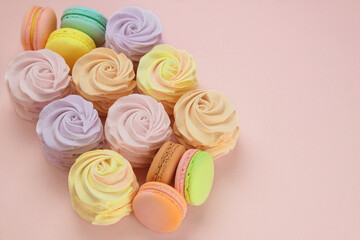 Macaroons and marshmallows in pink background. Traditional colored sweet desserts for the holiday. Flat lay. Copy space.