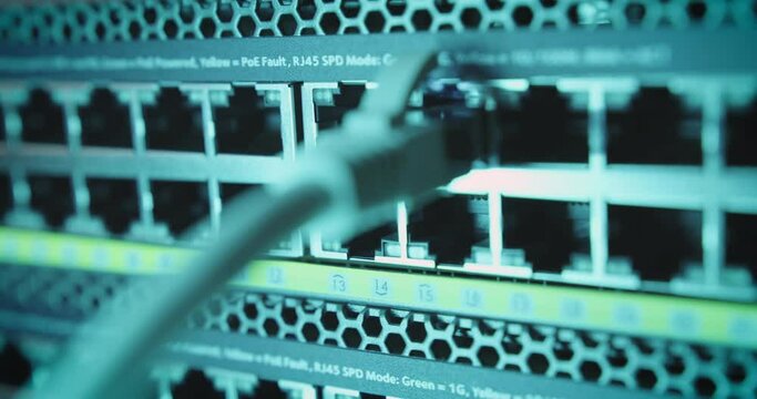 Close-up of hand plugging Ethernet cable into port of network internet switch
