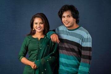 Portrait of a happy cheerful young couple posing on dark background. Attractive man and woman being playful.