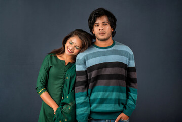Portrait of a happy cheerful young couple posing on dark background. Attractive man and woman being playful.