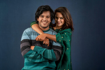 Portrait of a happy cheerful young couple posing on dark background. Attractive man and woman being playful.
