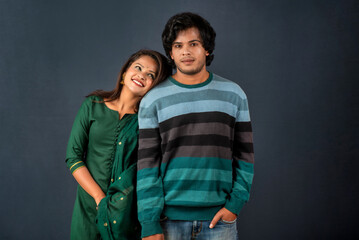 Portrait of a happy cheerful young couple posing on dark background. Attractive man and woman being playful.