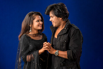 Portrait of a happy cheerful young couple posing on dark background. Attractive man and woman being playful.