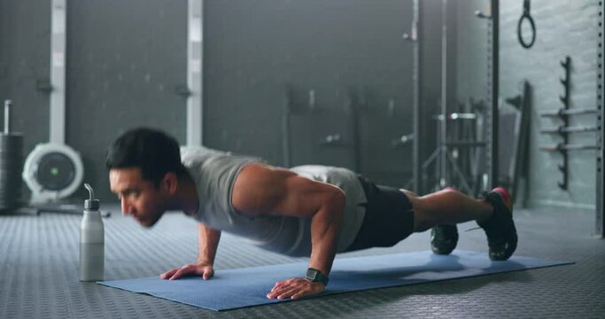 Fitness, man and pushups for muscle, exercise or training workout for strength or power at the gym. Athletic male in sport exercising lifting body with arms on the floor for strong muscles indoors