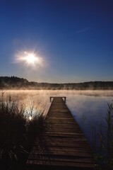 Beautiful summer morning landscape. Wooden pier on the lake shore in the misty morning scenery. Photo taken in Michala Gora, Poland.