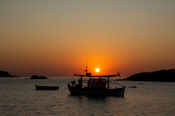 Boats in the calm sea at sunrise in Greece