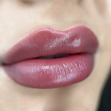 permanent makeup on the lips of a young woman of a delicate peach shade close-up