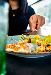 woman hand holding fork and knife eat chicken breast meat with potato in a plate
