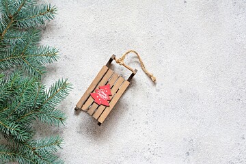 Christmas tree branch on a gray background, festive mood, gift season. Decorative wooden sled for decoration , toys. Winter holidays concept. Top view and copy space.